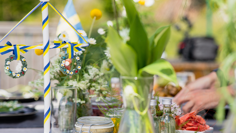 Midsommarbord Midsommarbord med majstang, blommor och sillburkar